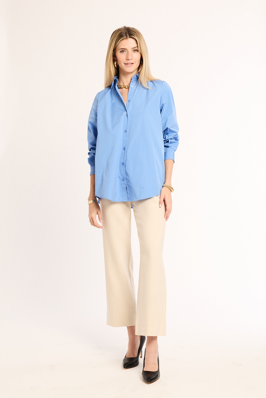 Woman wearing a light blue shirt and beige pants on a white background