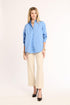 Woman wearing a light blue shirt and beige pants on a white background