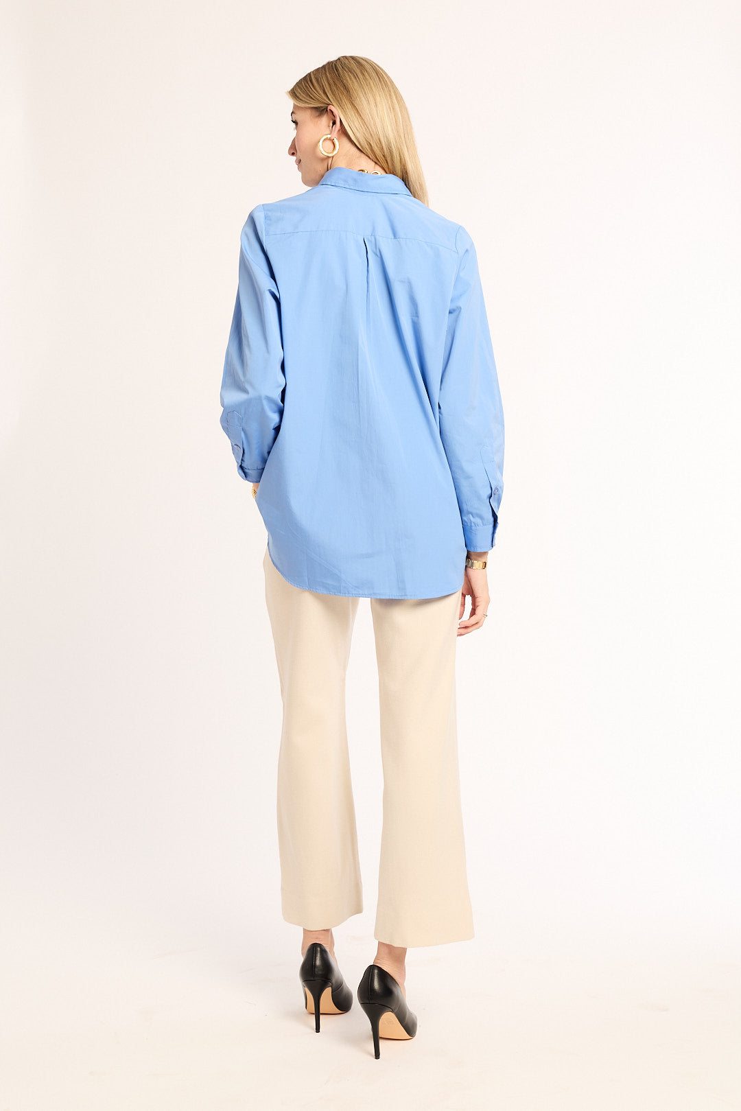 Woman wearing a light blue shirt and beige pants on a white background