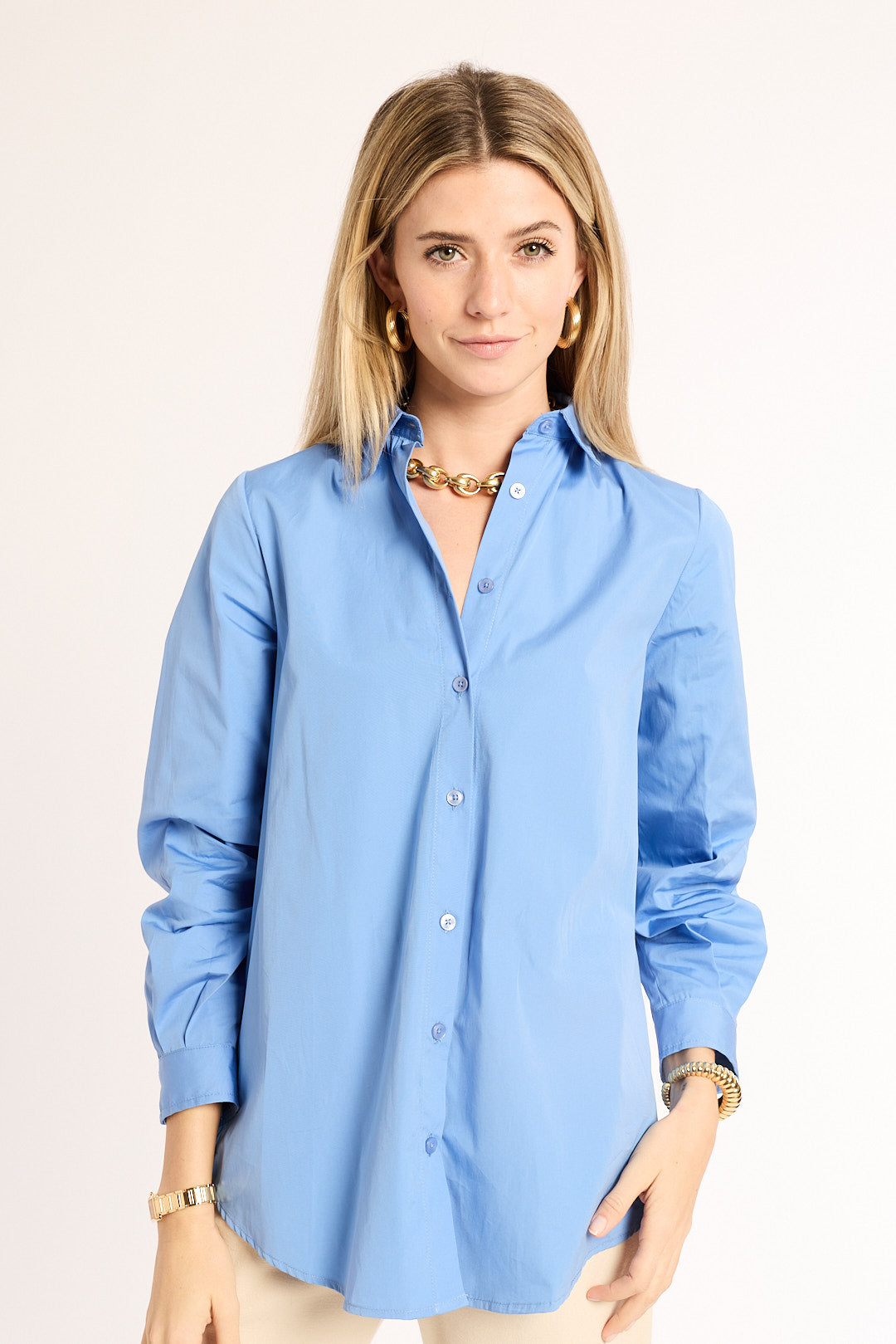 Woman wearing a light blue button-up shirt against a plain background