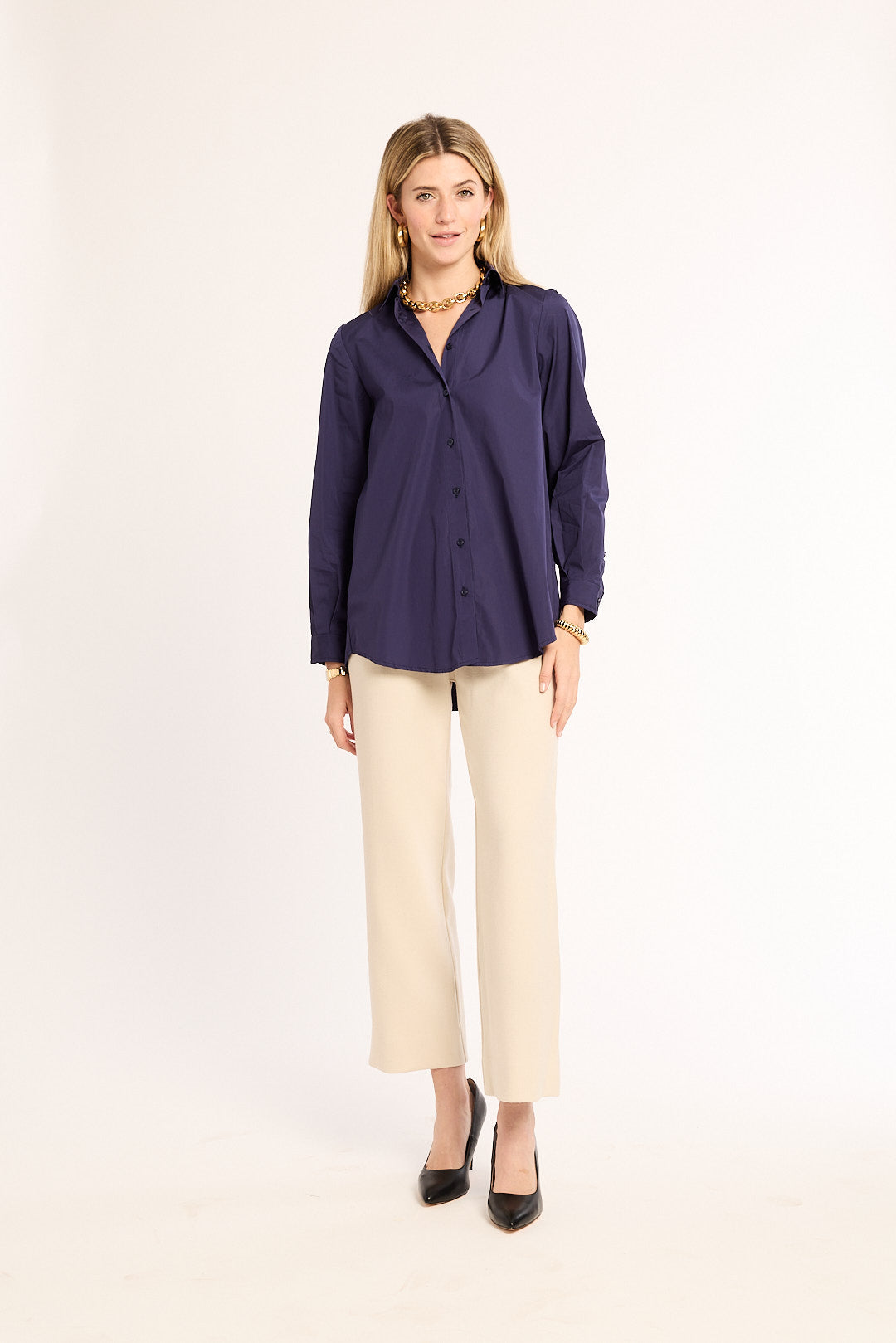 Woman wearing a navy blue shirt and beige pants on a white background