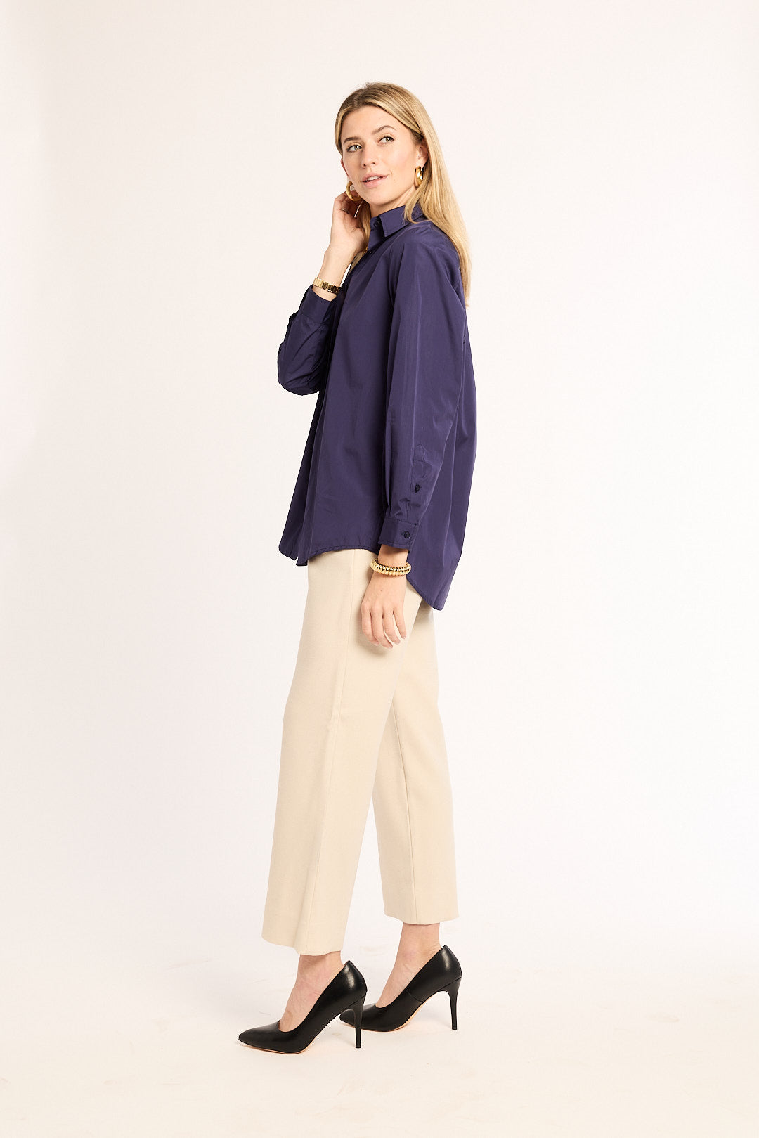 Woman wearing a navy blue blouse and beige pants on a white background