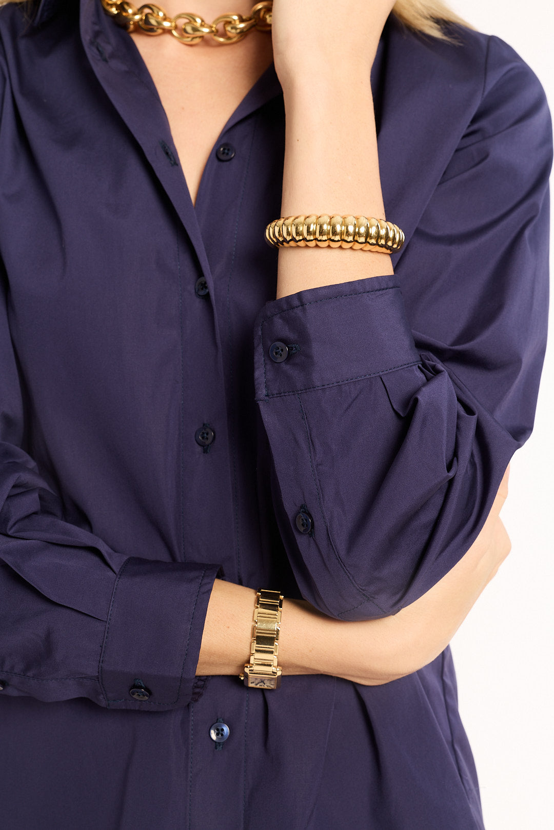 Navy blue shirt with gold jewelry on a white background