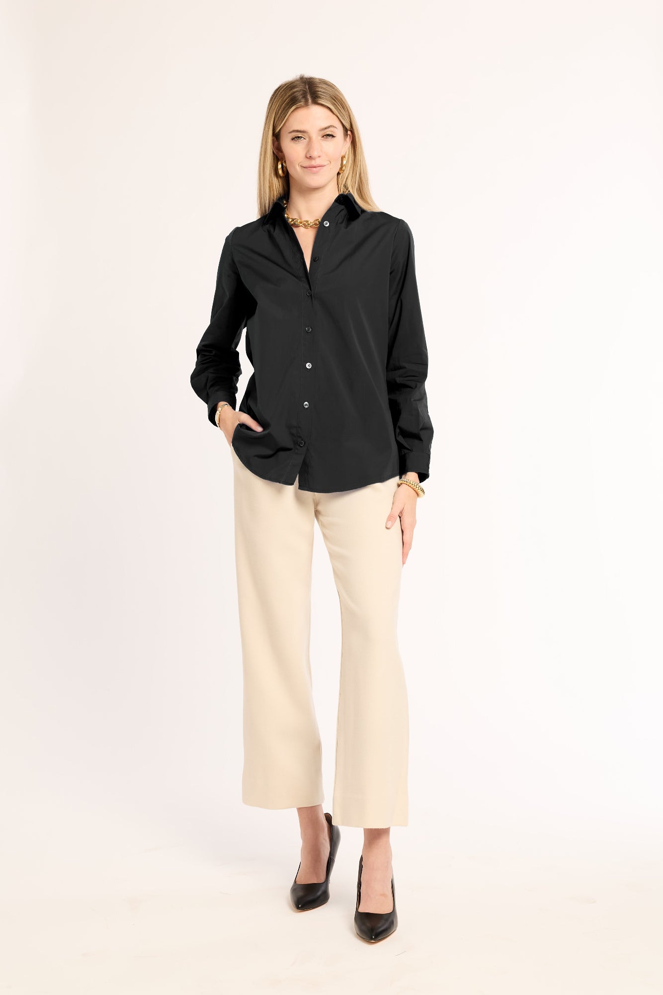 Woman wearing a black shirt and beige pants on a white background