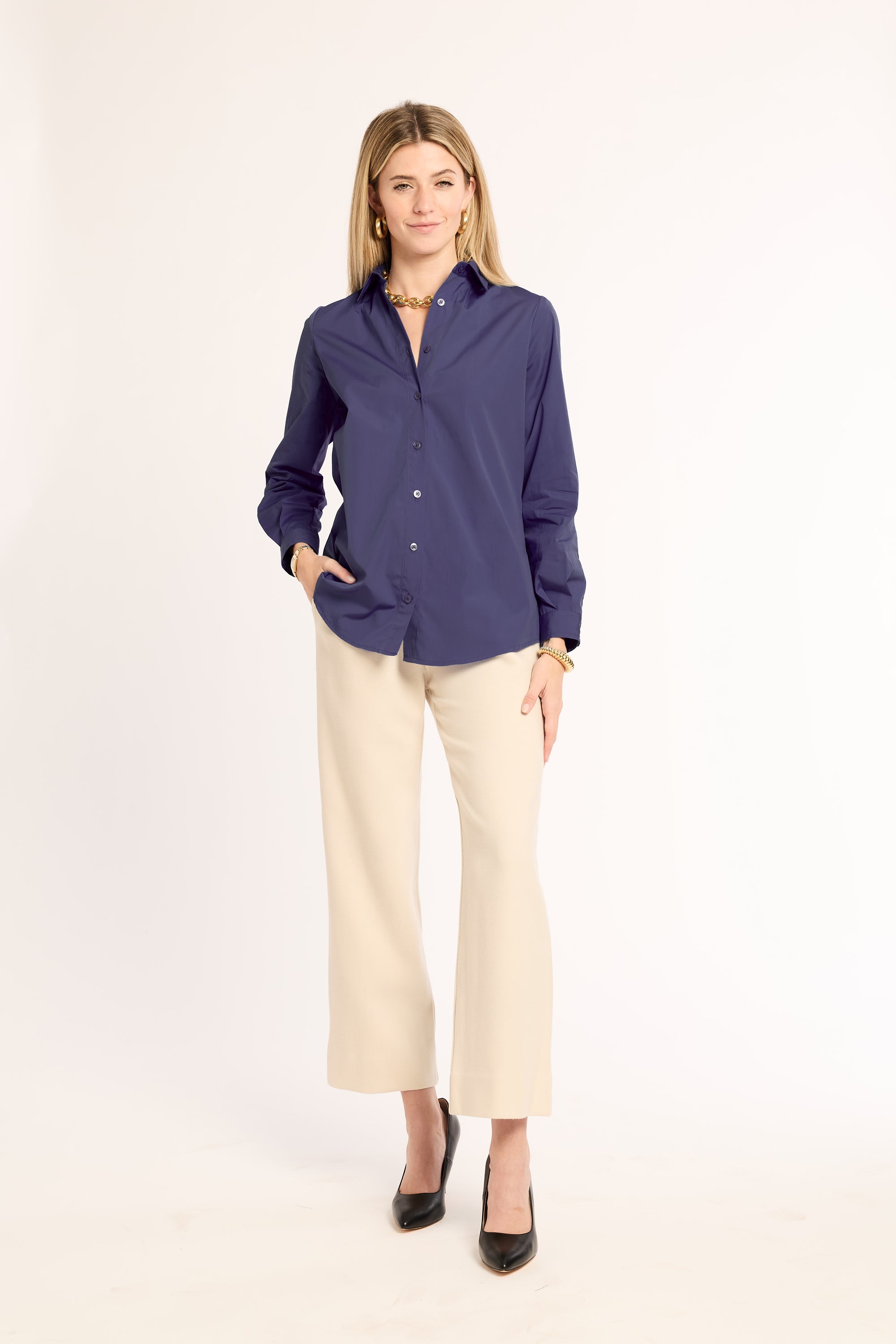 Woman wearing a navy blue shirt and beige pants on a white background