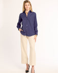 Woman wearing a navy blue shirt and beige pants on a white background