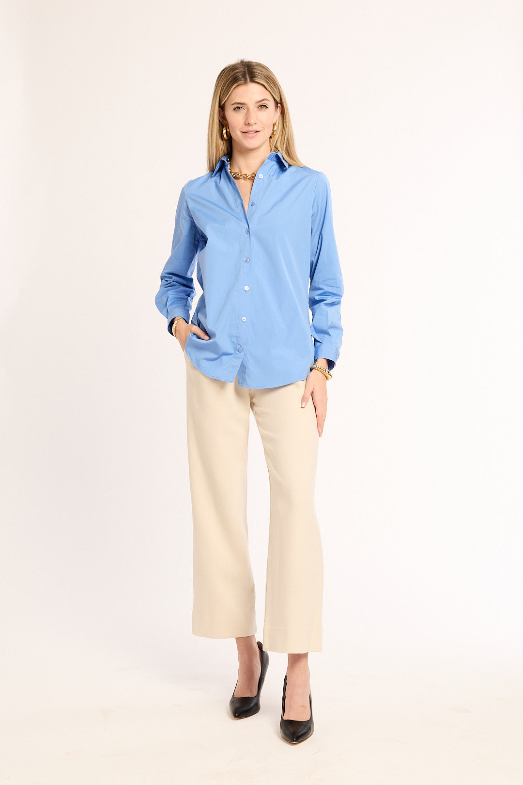 Woman wearing a blue shirt and beige pants on a white background