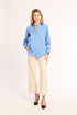 Woman wearing a blue shirt and beige pants on a white background
