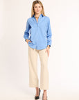 Woman wearing a blue shirt and beige pants on a white background