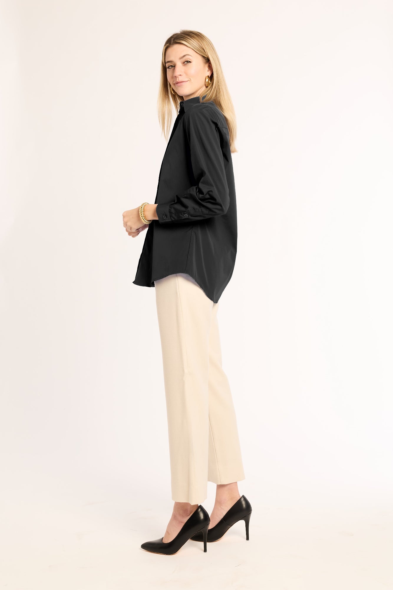 Woman wearing a black top and beige pants on a white background