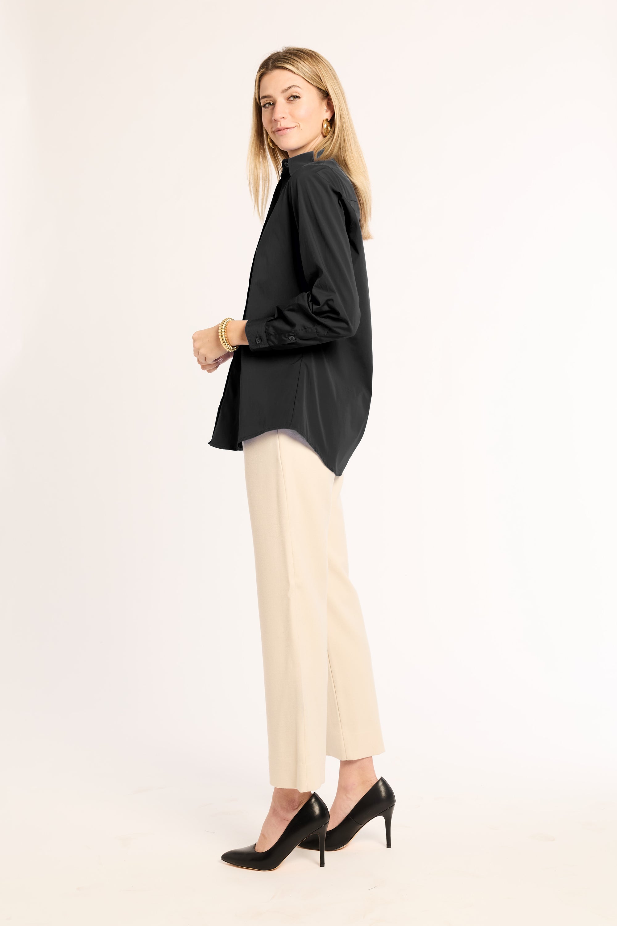 Woman wearing a black top and beige pants on a white background
