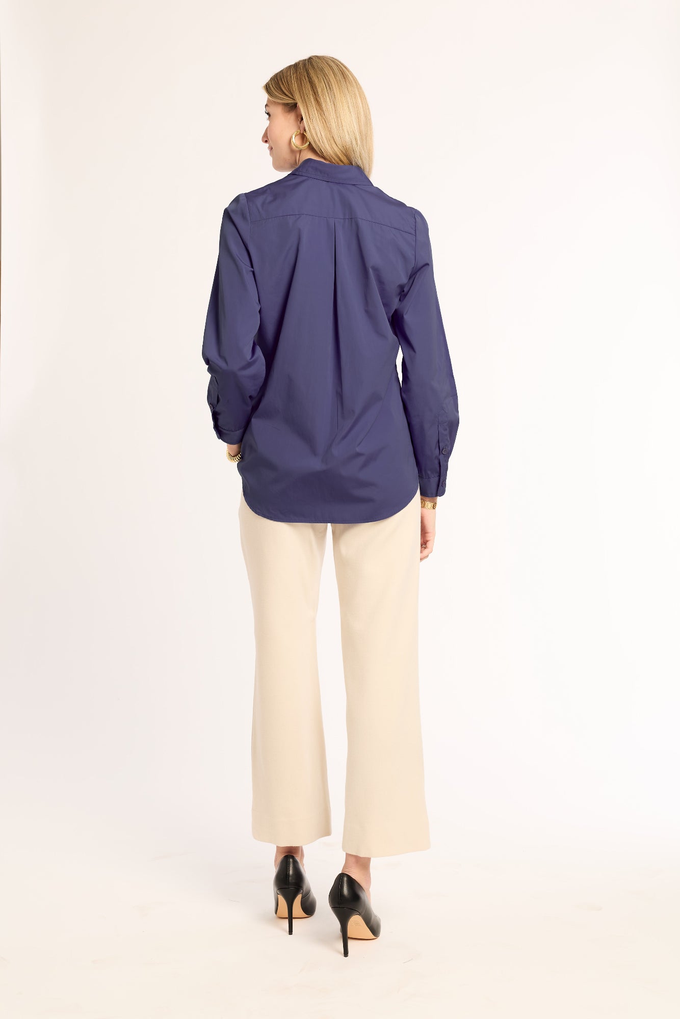 Woman wearing a navy shirt and beige pants on a white background