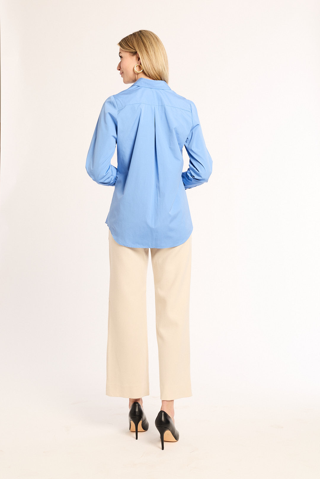 Woman wearing a light blue shirt and beige pants on a white background