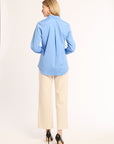 Woman wearing a light blue shirt and beige pants on a white background