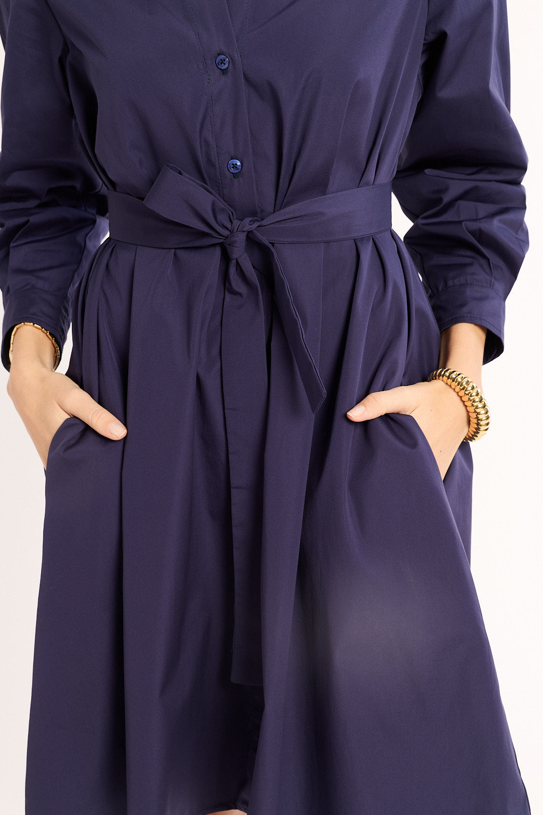 Navy blue dress with a belt and long sleeves on a white background