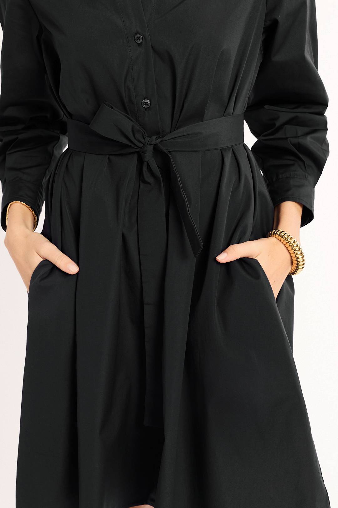 Black dress with a belt worn by a person on a white background
