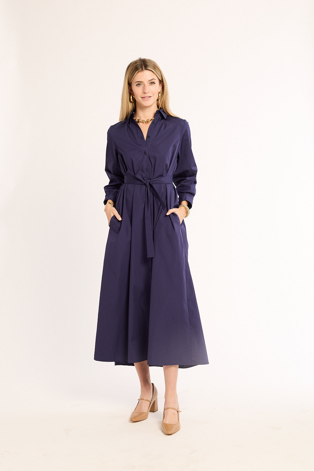 Woman wearing a navy dress with a belt on a white background