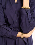 Navy blue shirt with a tie waist worn by a person, with gold bracelets on wrists.