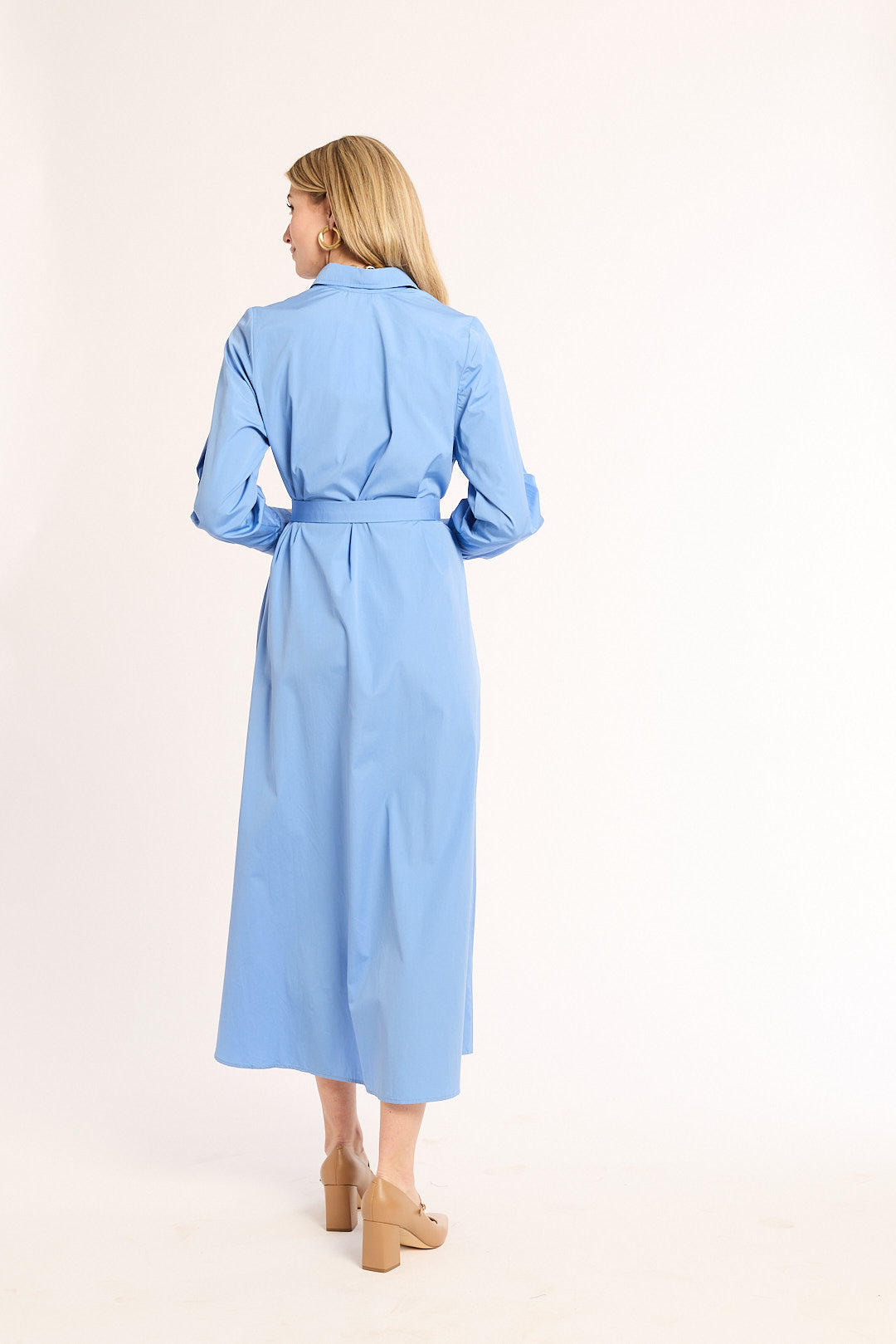 Woman wearing a light blue dress with a belt on a white background
