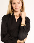 Woman wearing a black shirt and gold jewelry on a plain background