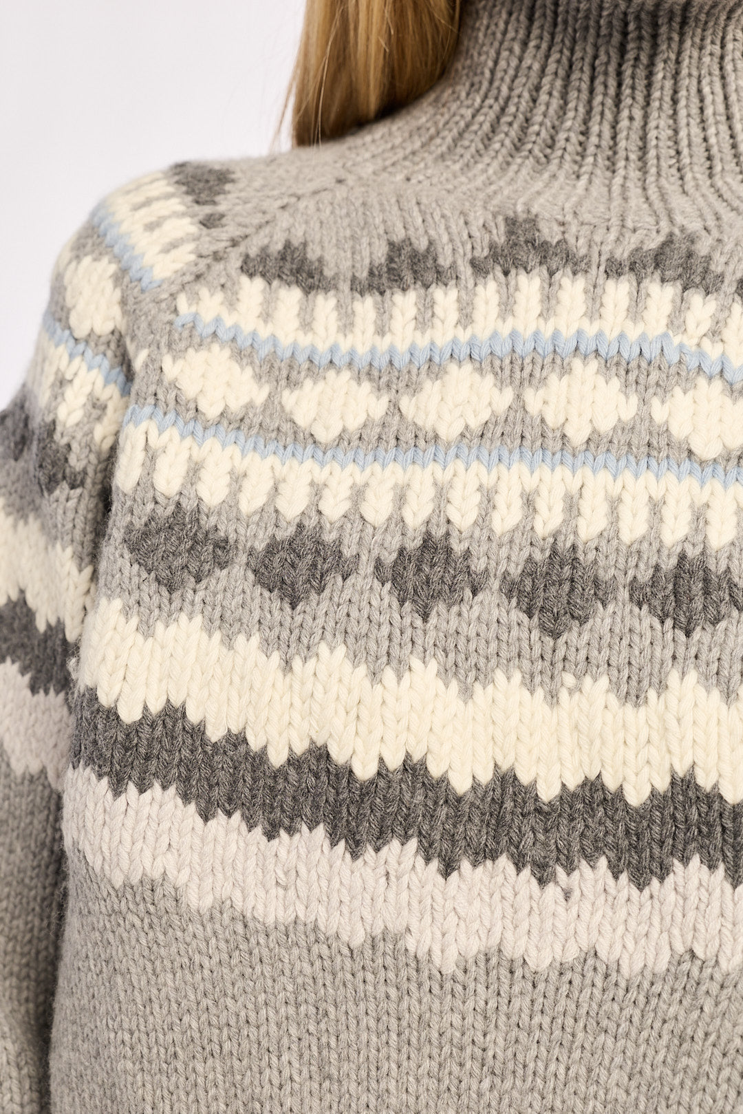 Close-up of a patterned sweater with gray, white, and blue colors.
