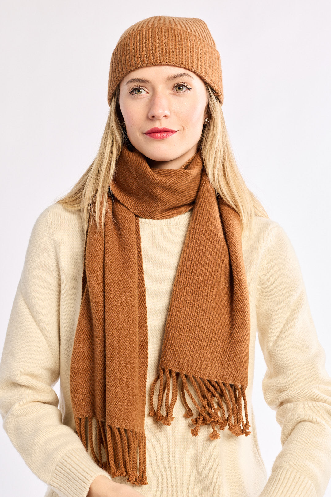 Woman wearing a brown knit hat and scarf on a white background