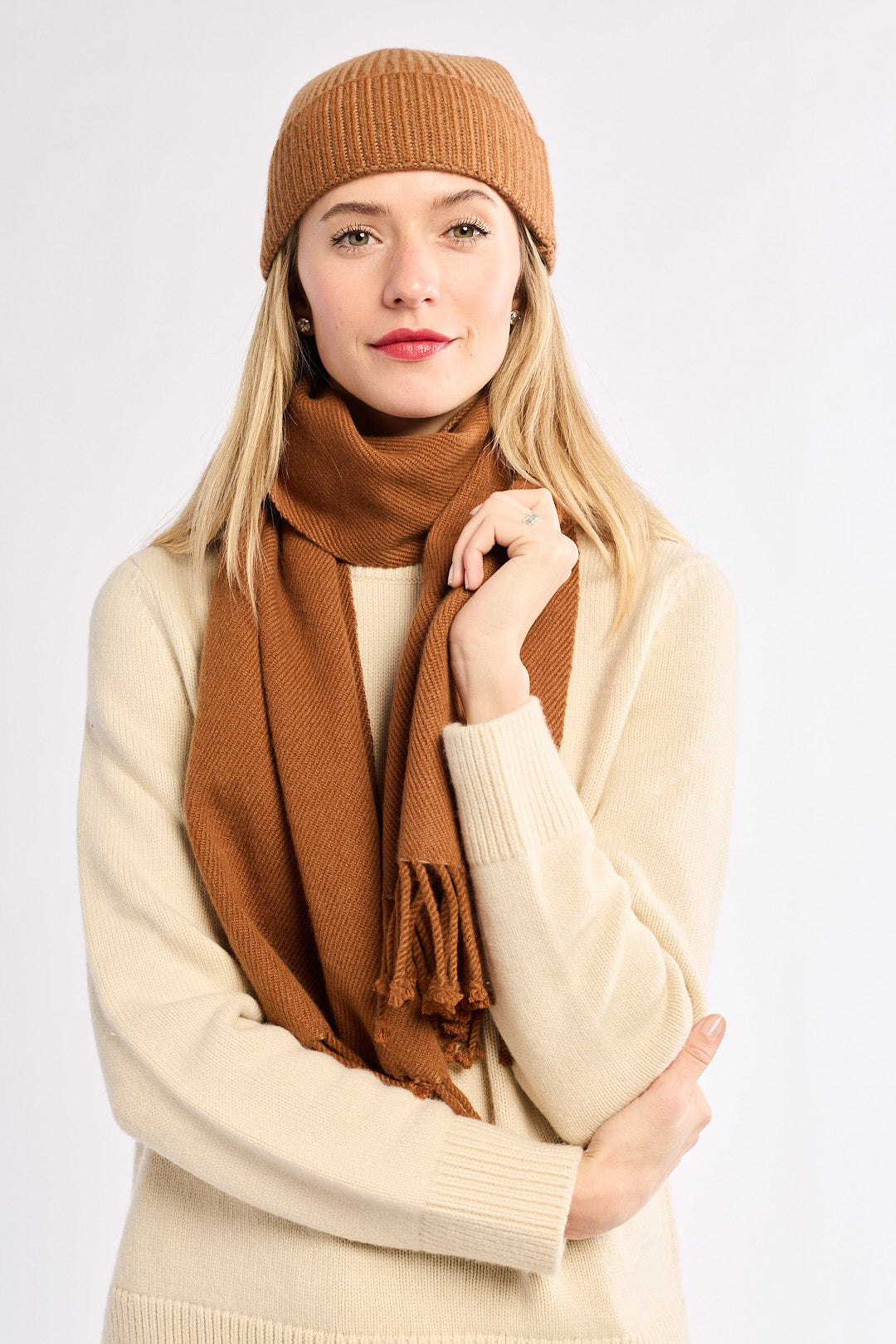 Woman wearing a brown knit hat and scarf on a white background