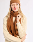 Woman wearing a brown knit hat and scarf on a white background