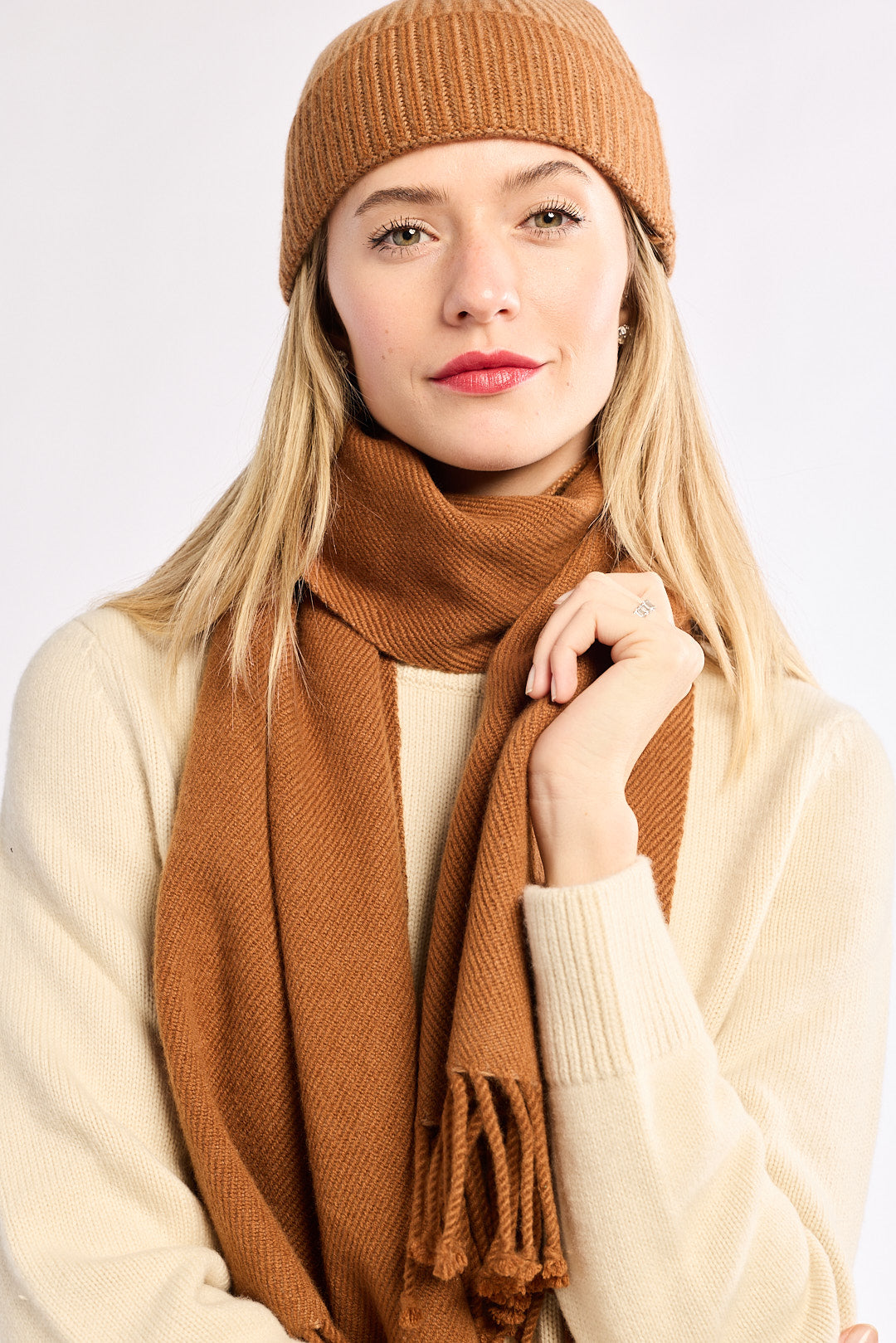 Woman wearing a brown knit hat and scarf on a white background