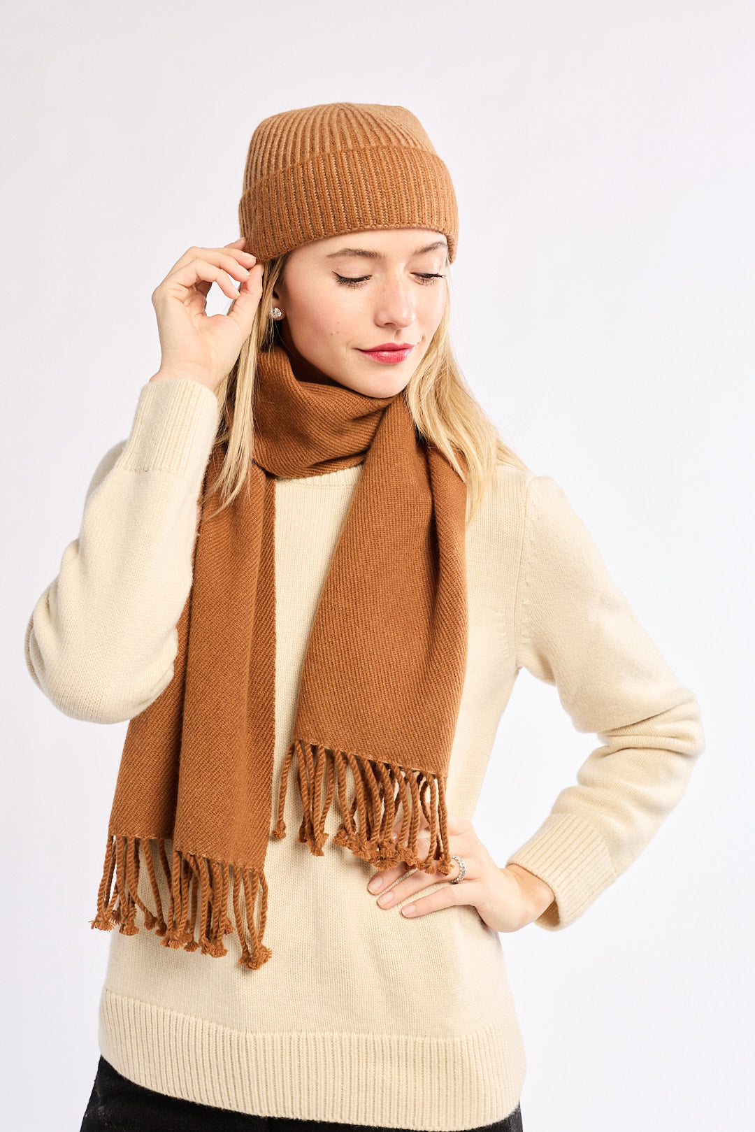 Woman wearing a brown knit hat and scarf on a white background