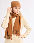 Woman wearing a brown knit hat and scarf on a white background