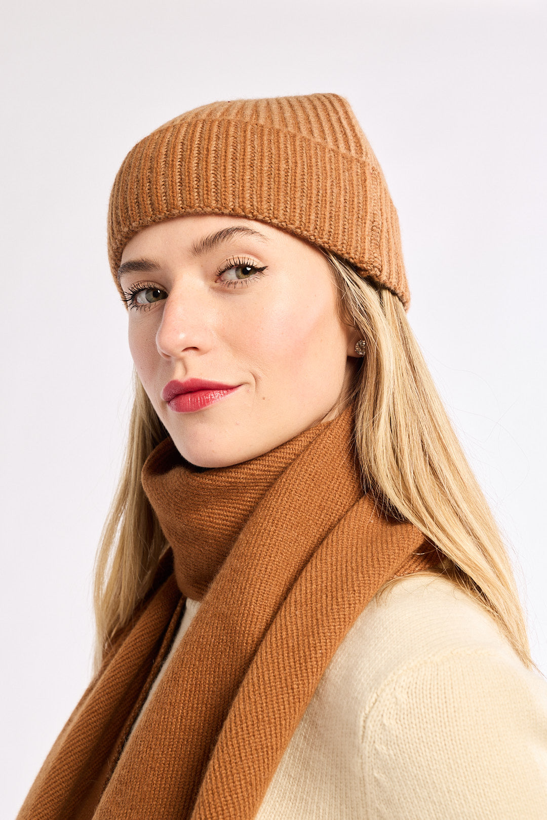 Woman wearing a brown knit hat and scarf on a white background