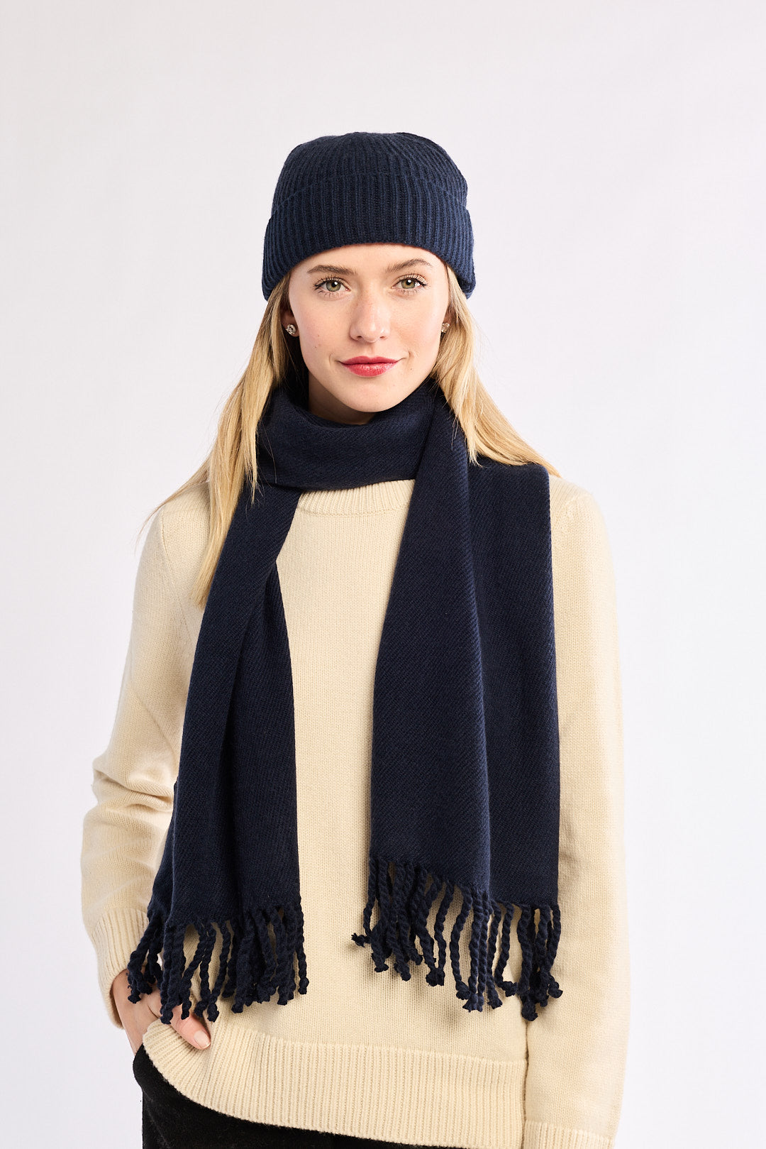 Woman wearing a navy scarf and beanie on a white background
