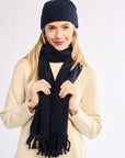 Woman wearing a navy scarf and hat on a white background