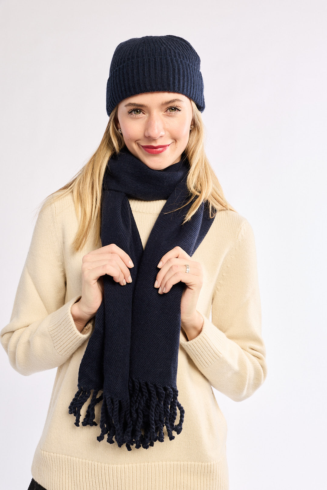 Woman wearing a navy blue scarf and hat on a white background