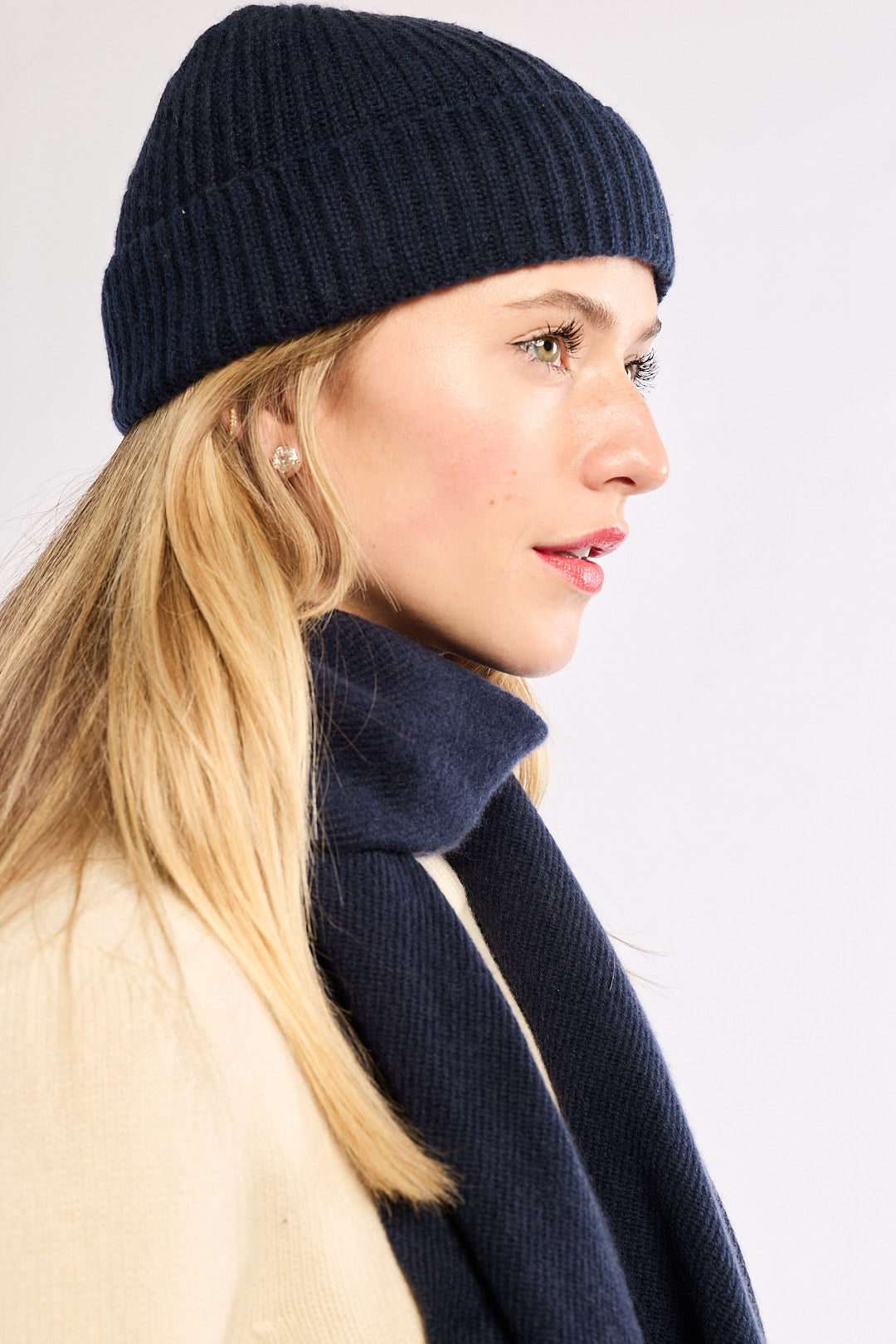 Woman wearing a navy knit hat and scarf on a white background