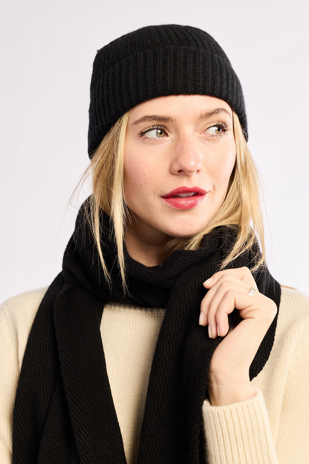Woman wearing a black knit hat and scarf against a white background
