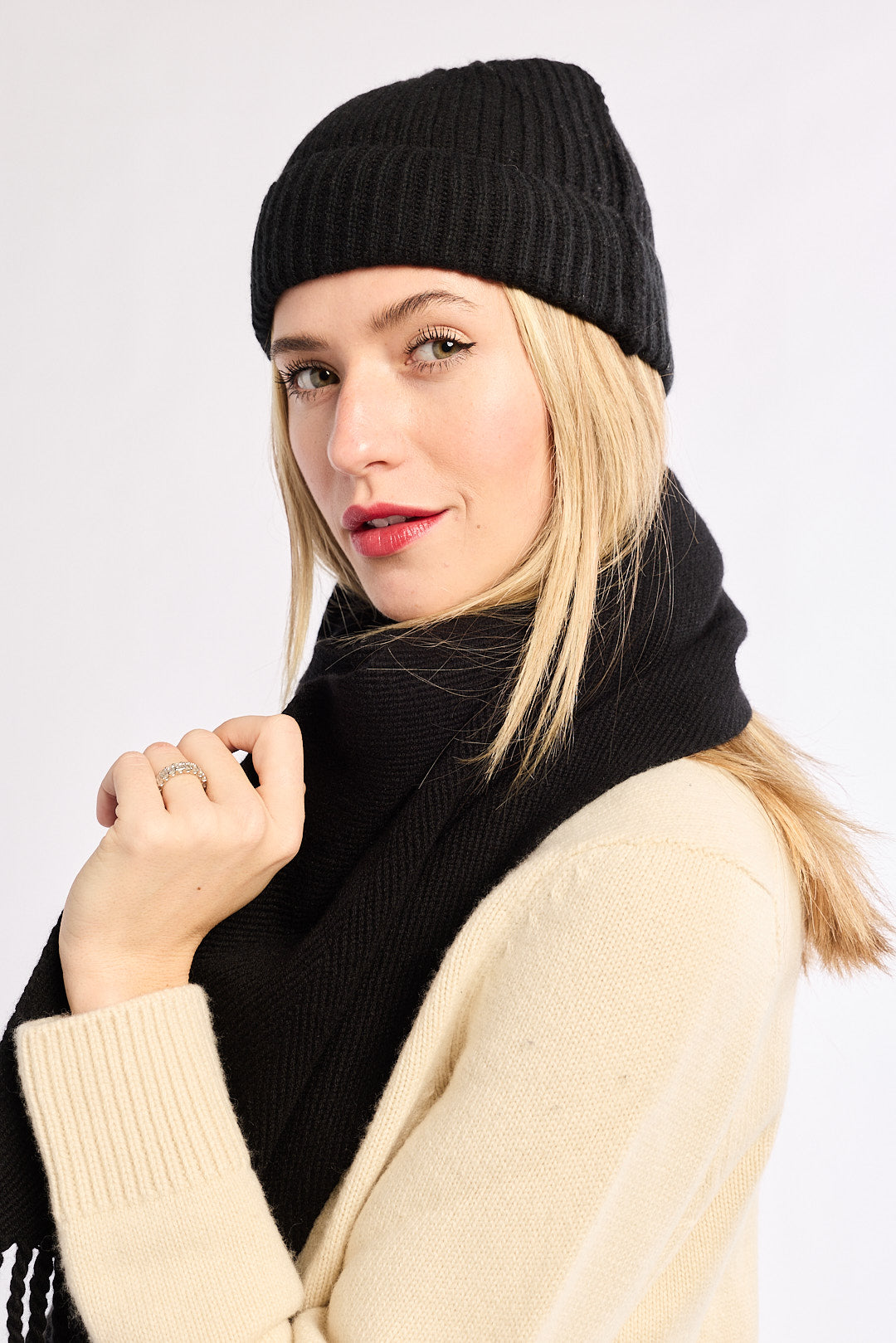 Woman wearing a black knit hat and scarf with a white background