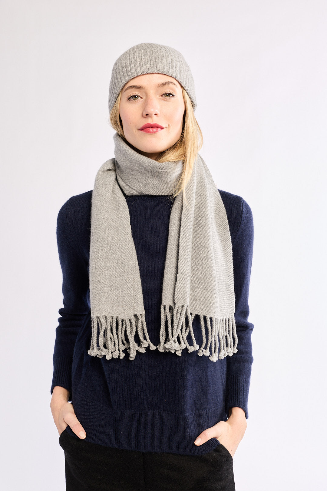 Woman wearing a gray scarf and beanie on a white background