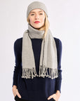 Woman wearing a gray scarf and beanie on a white background