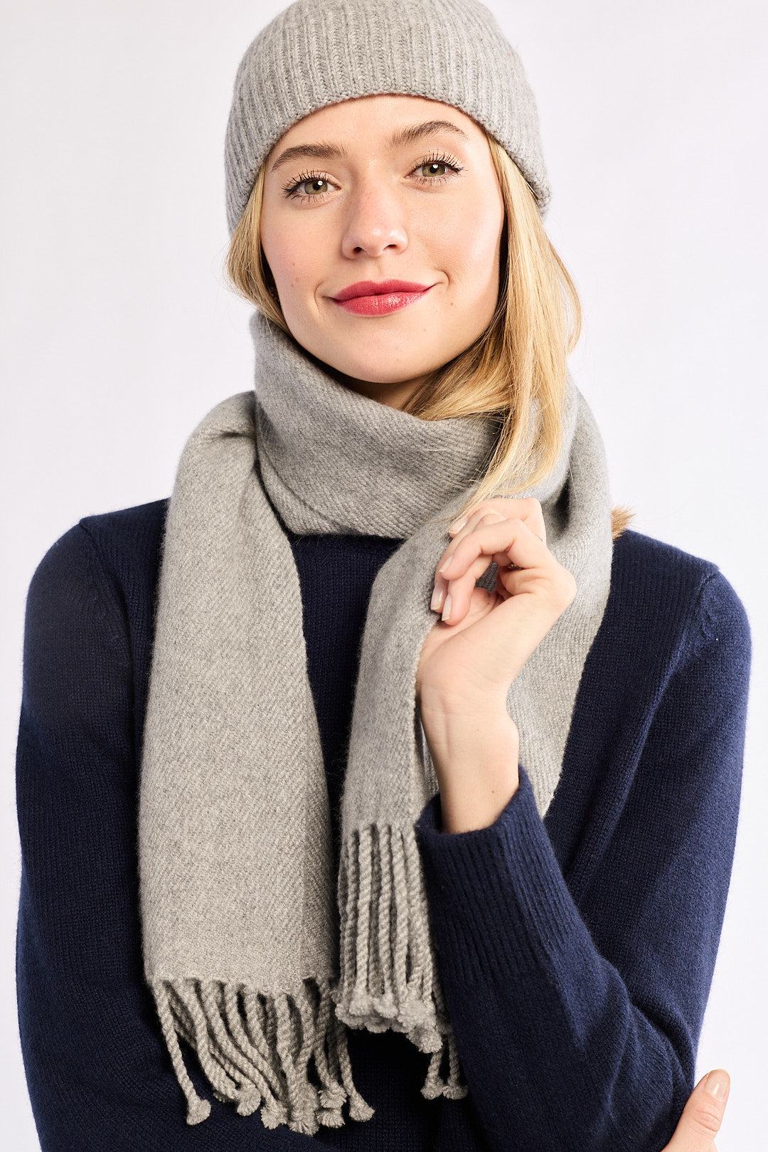 Woman wearing a gray knit hat and scarf on a white background