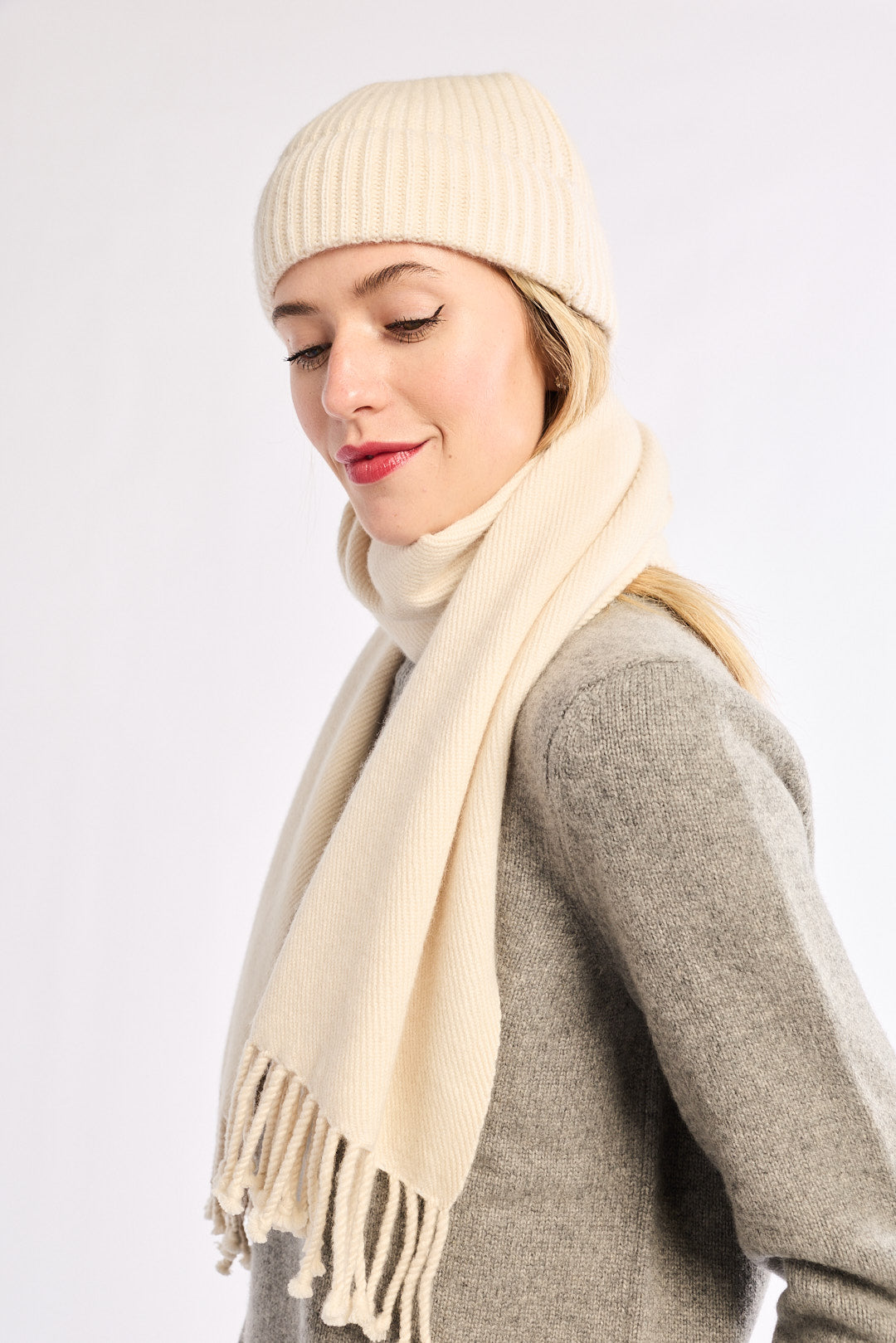 Woman wearing a beige knit hat and scarf on a white background