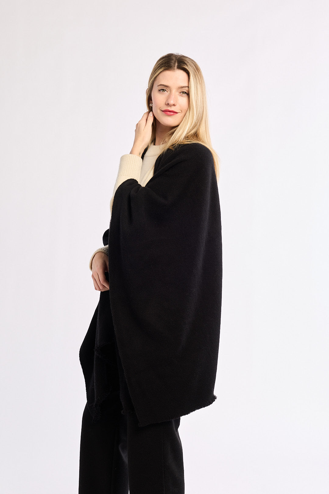 Woman wearing a black poncho over a white background