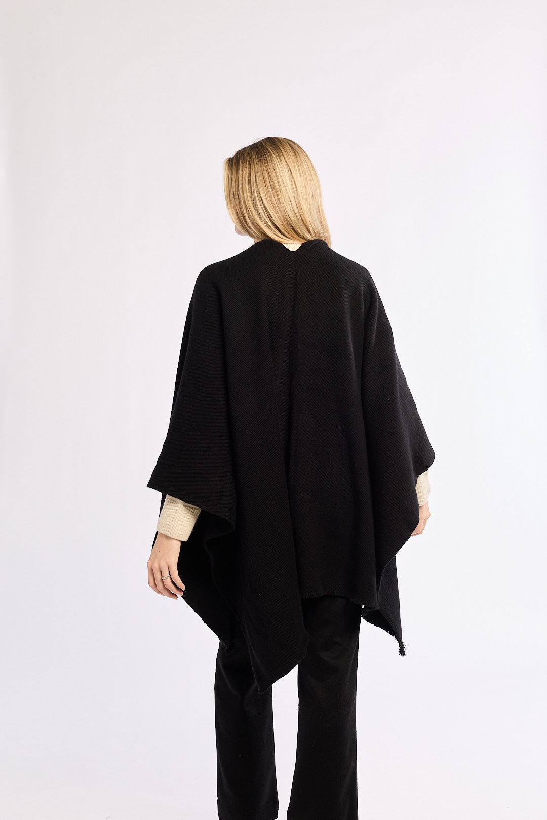 Person wearing a black poncho against a white background
