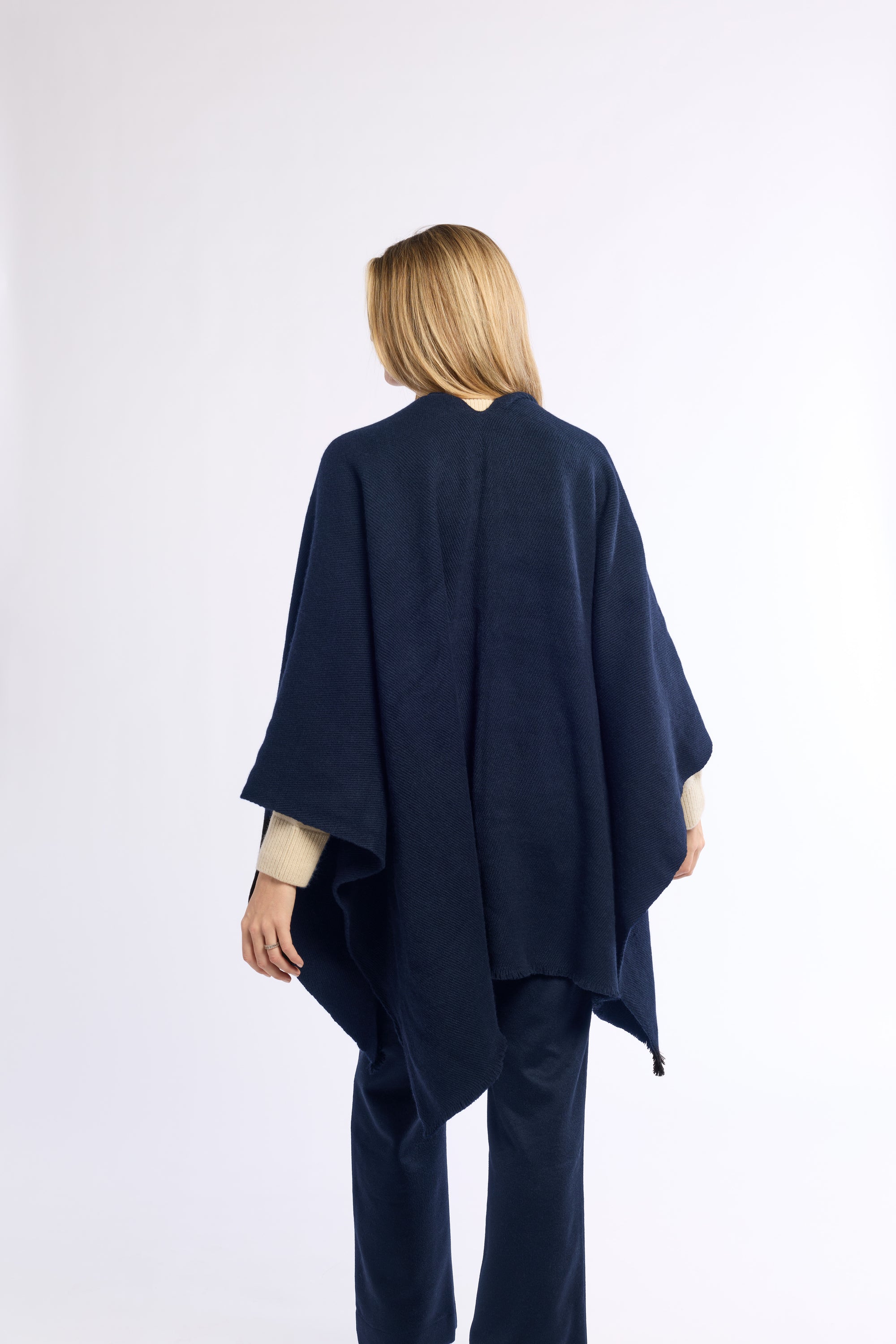 Person wearing a navy blue poncho on a white background