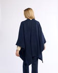 Person wearing a navy blue poncho on a white background