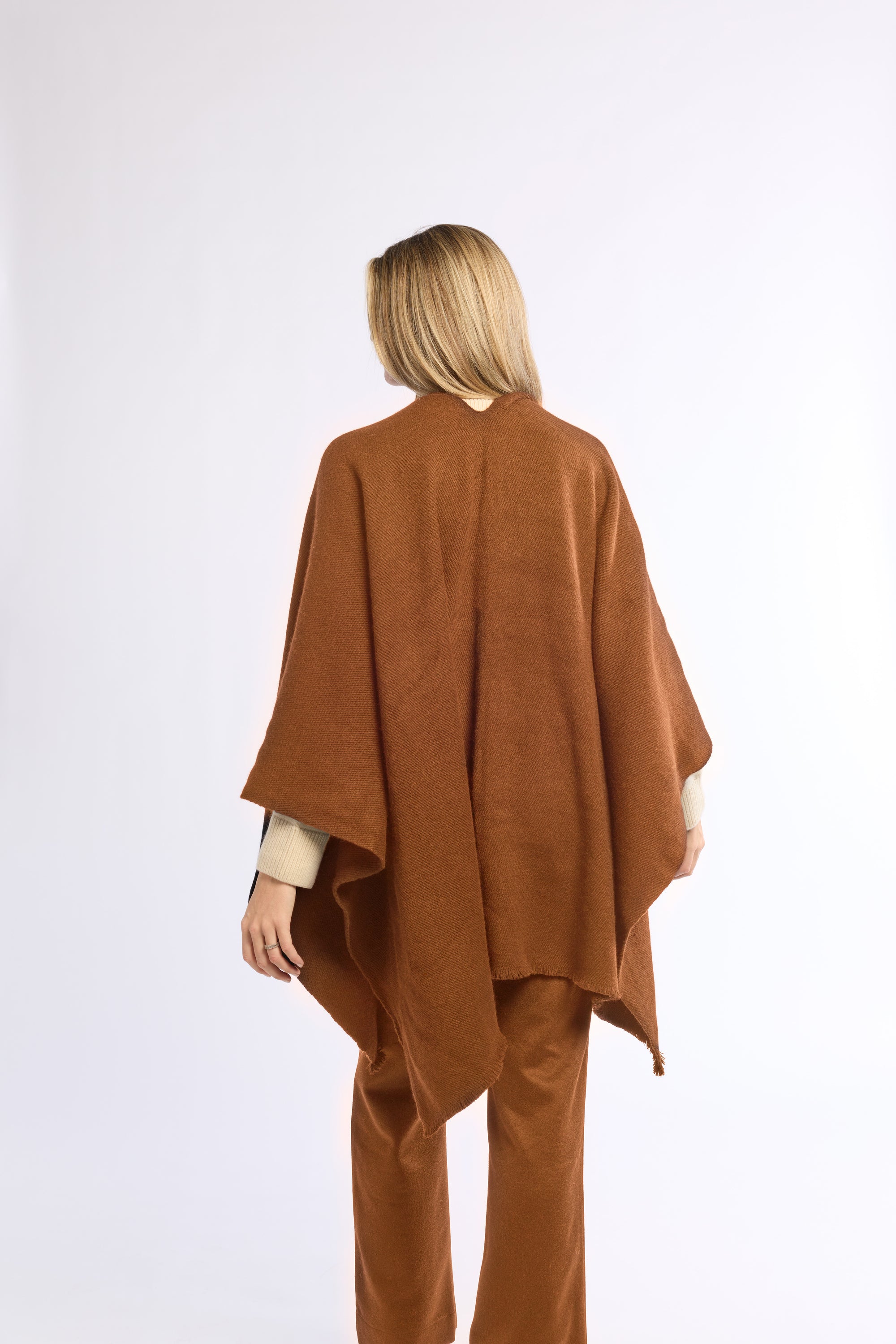 Person wearing a brown poncho and pants on a white background