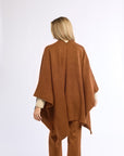Person wearing a brown poncho and pants on a white background