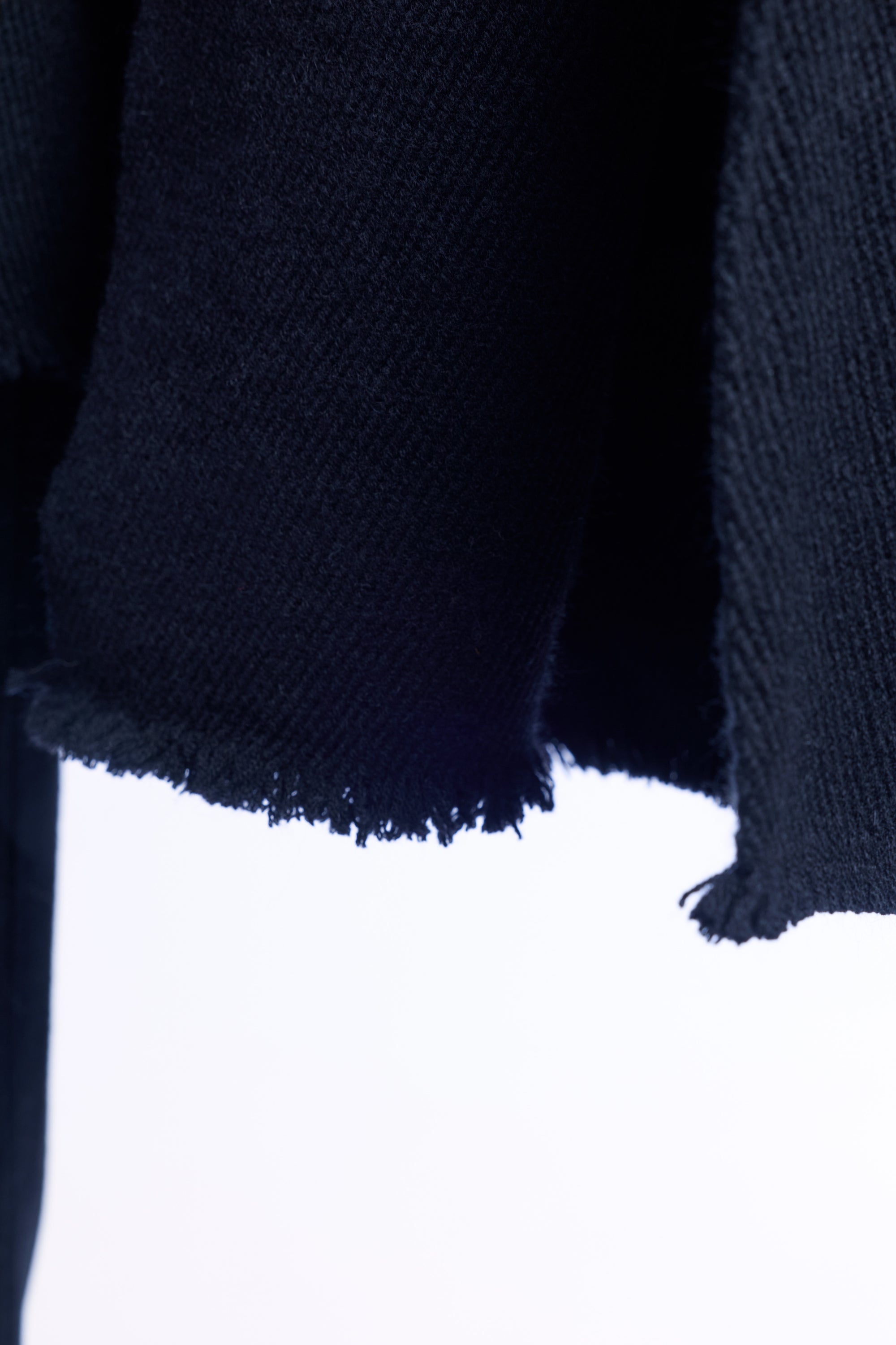 Close-up of a dark blue sweater with frayed edges on a white background