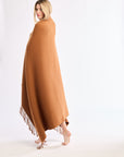 Woman wearing a brown poncho with tassels on a white background